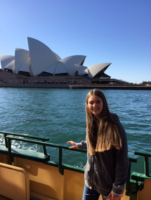 Niña en un ferry frente a Opera House de Sidney en Australia