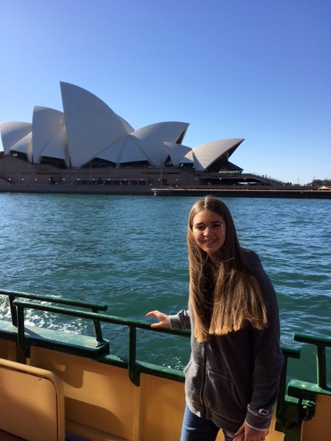 Niña en un ferry frente a Opera House de Sidney en Australia