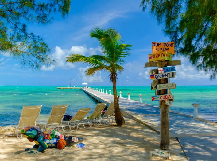 Playa Rum Point con reposeras y cartel de colores en Islas Caimán