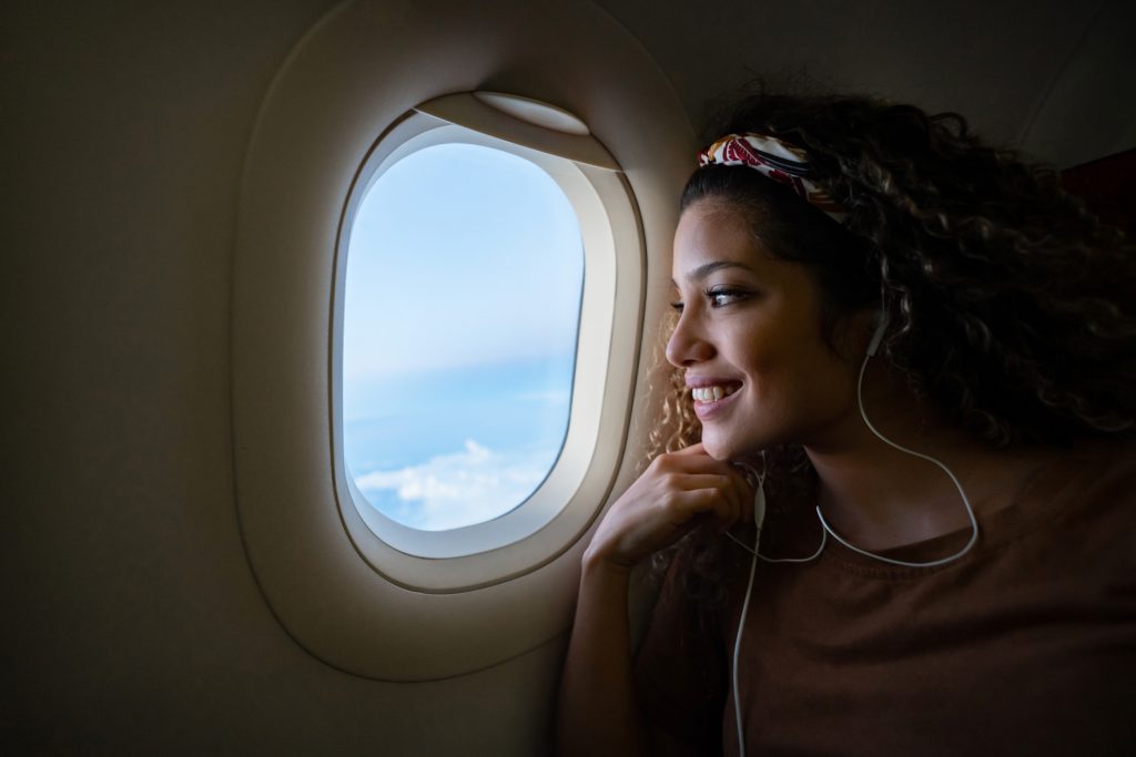 Vuelos baratos y mujer mirando por la ventana de un avión