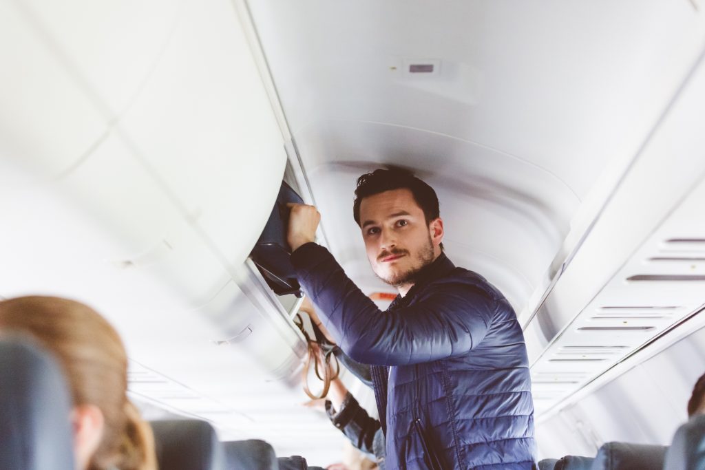 Hombre guardado su equipaje en la cabina